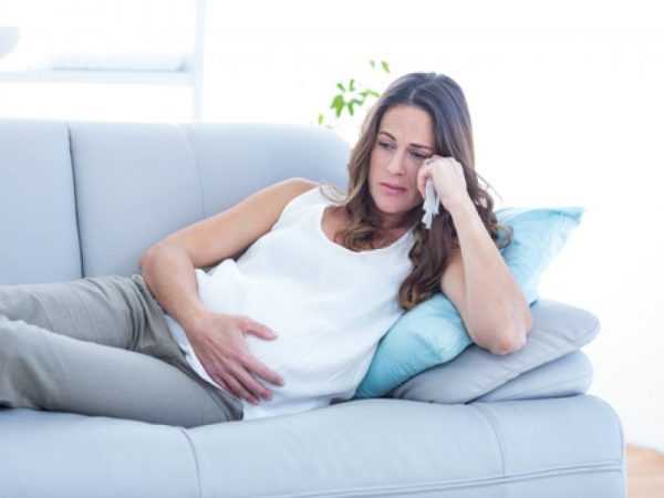 беременная полулежит на диване с грустным лицом