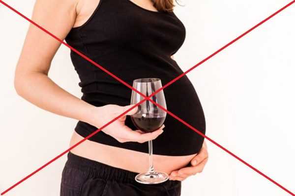 Беременная держит в руке бокал вина