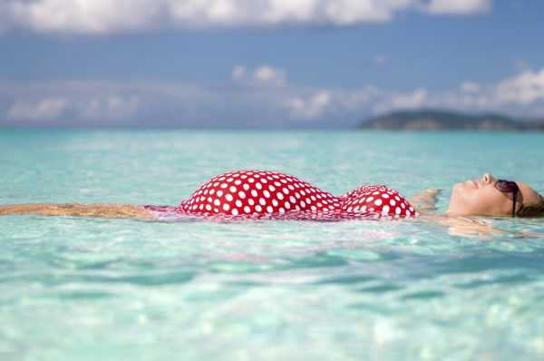 Беременная девушка лежит на воде в море