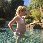Беременная девушка на 27 неделе стоит в воде