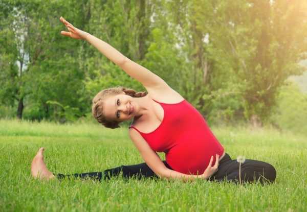 Беременная девушка сидит на траве