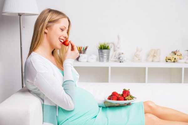 беременная подносит ко рту клубнику