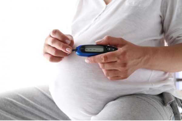 Беременная измеряет уровень сахара глюкометром