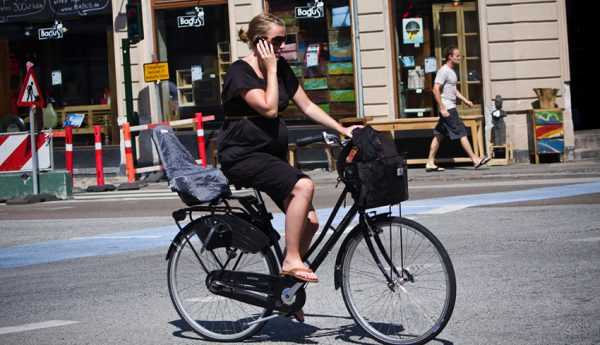 Беременная на большом сроке едет на велосипеде по улице европейской страны