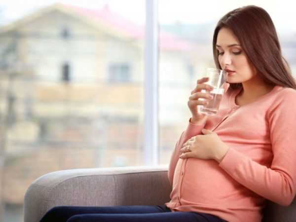 беременная подносит стакан воду ко рту