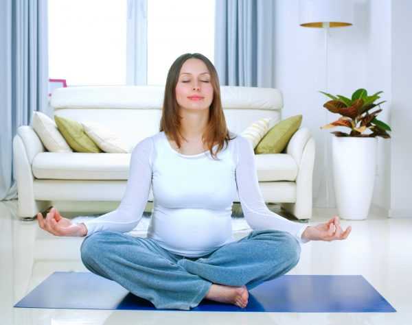 Беременная сидит в позе для йоги
