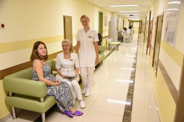 беременная сидит на диване с врачами в медицинском центре