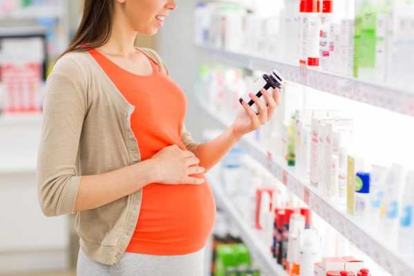 Беременная выбирает витамины в аптеке