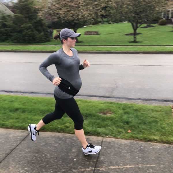 Беременная женщина бежит трусцой по тротуару