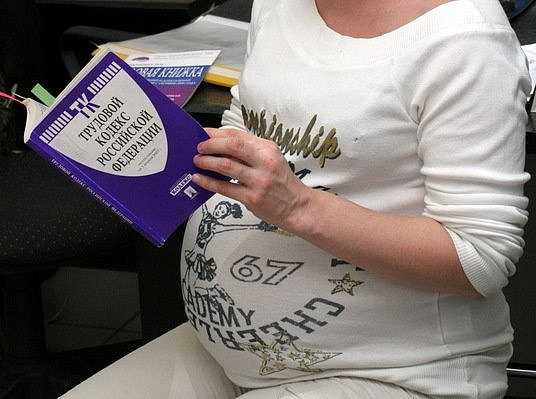 Беременная женщина читает трудовой кодекс РФ