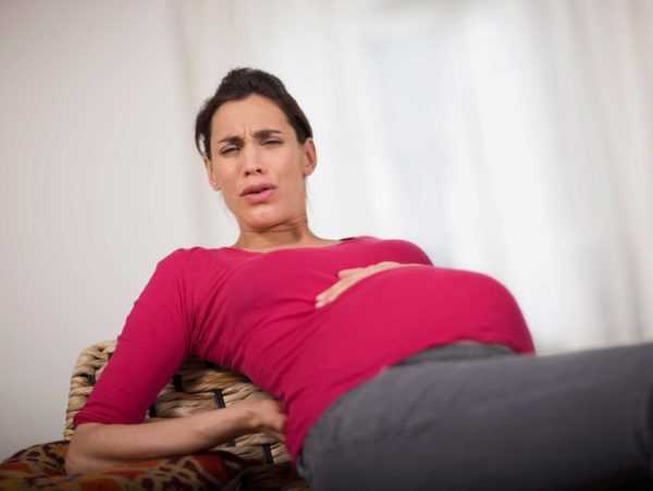 Беременная женщина держится за живот как во время схваток