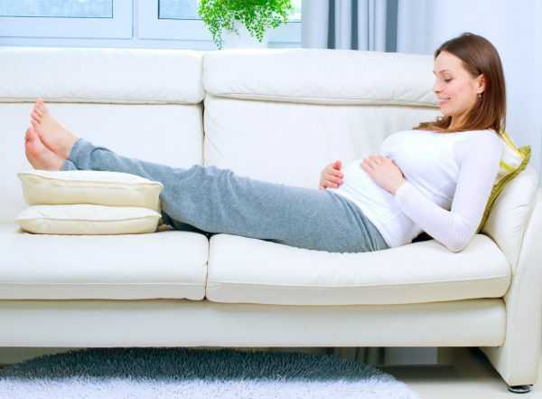 Беременная женщина лежит на диване
