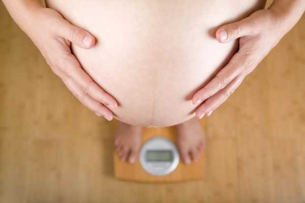 Беременная женщина стоит на весах