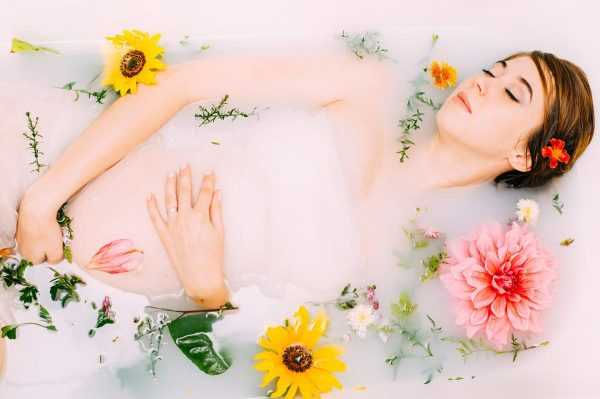 Будущая мама лежит в ванне с цветами