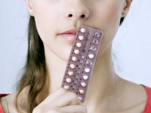 Женщина держит противозачаточные таблетки