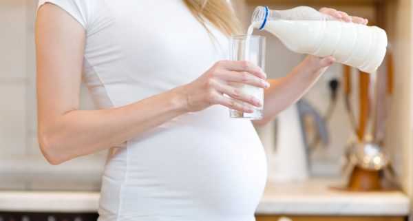 Беременная женщина наливает в стакан молоко