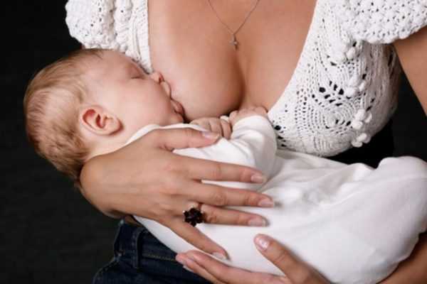 Мама кормит младенца грудью, держа его на руках