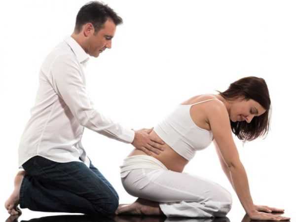 Специалист делает массаж спины беременной