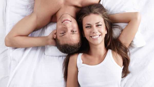 Мужчина и женщина лежат на кровати и улыбаются