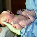 Новорождённый малыш на руках у врача
