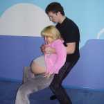 Мужчина держит беременную за подмышки