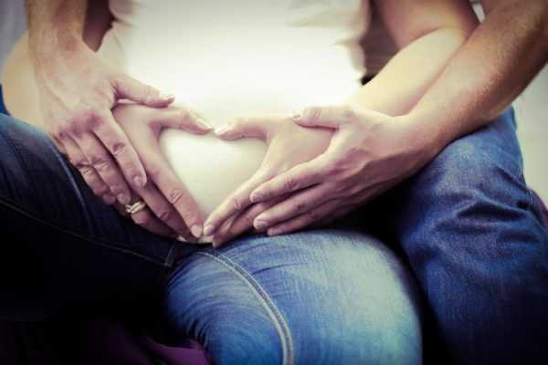 Мужские и женские руки на животе беременной