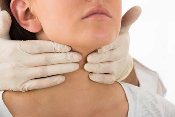 Руки врача на щитовидной железе женщины