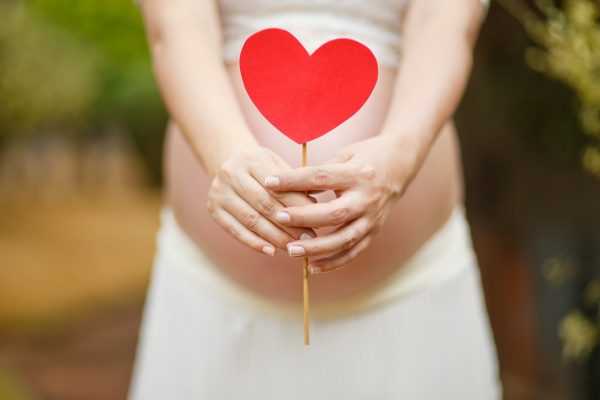 Беременная держит красное сердечко