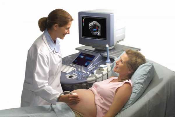 врач водит датчиком по животу беременной, на экране цветное видео