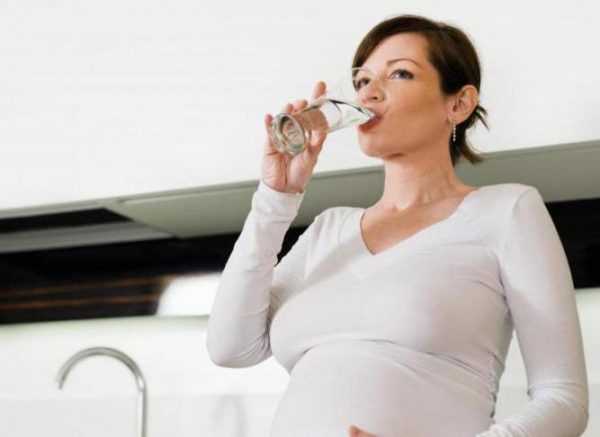 Беременная женщина пьёт воду из стакана