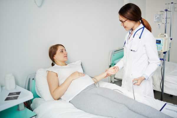 Беременная лежит в палате, рядом врач