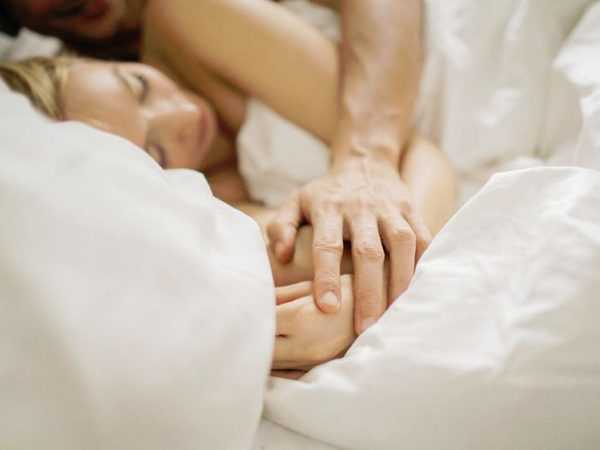 Супруги лежат в кровати и держатся за руки