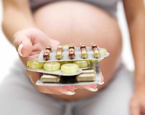 Таблетки в руке беременной женщины
