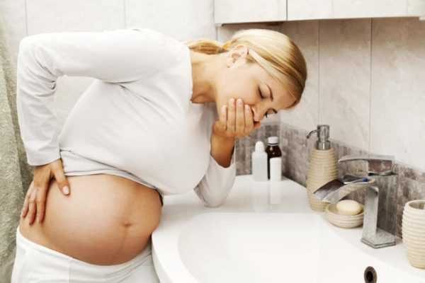 беременная закрывает рот ладонью над раковиной