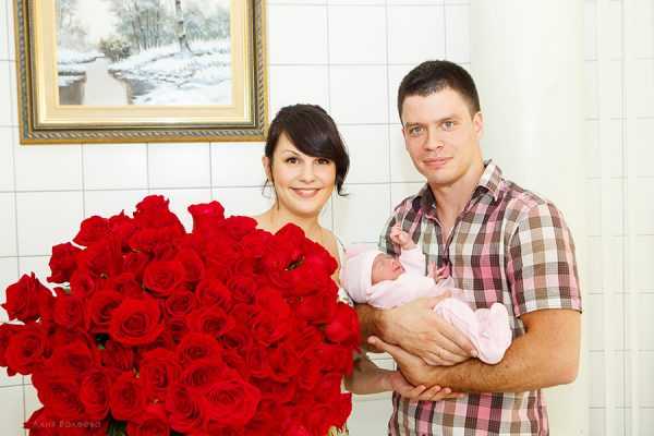 мама с огромным букетом роз и папа с малышом на руках