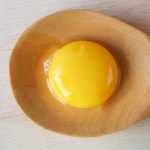 Яичный желток на большой деревянной ложке