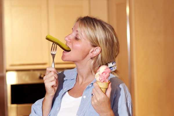Женщина ест одновременно солёный огурец и мороженое