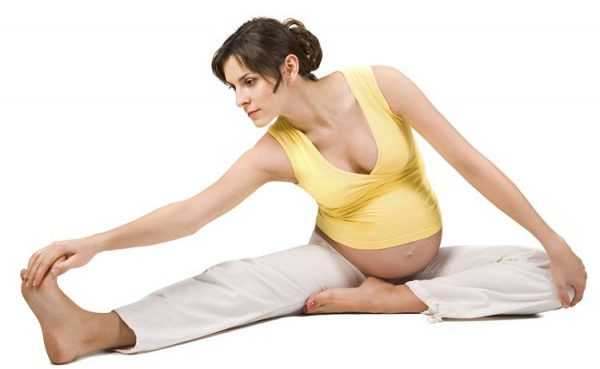 Беременная женщина делает гимнастическое упражнение